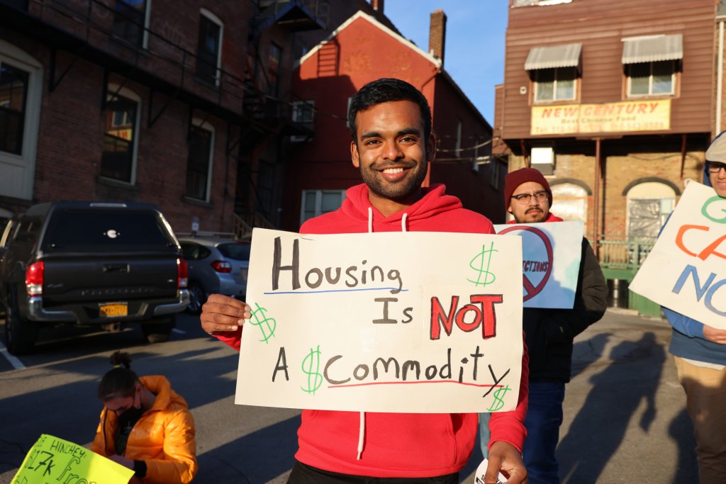 Person holding a sign that says `housing is not a commodity`